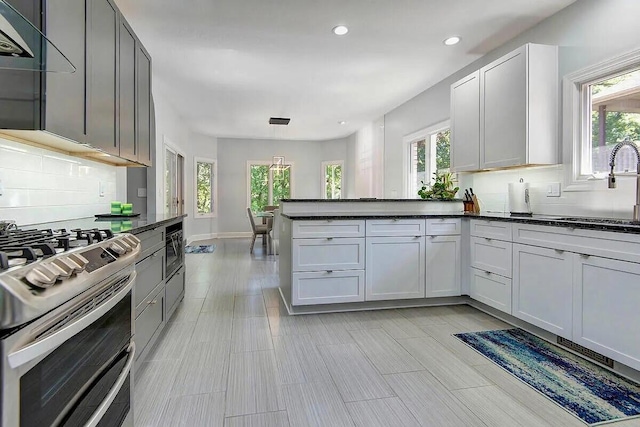 kitchen featuring white cabinetry, kitchen peninsula, backsplash, range with two ovens, and sink