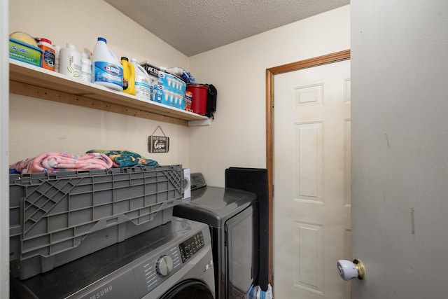 laundry area with washing machine and clothes dryer and a textured ceiling