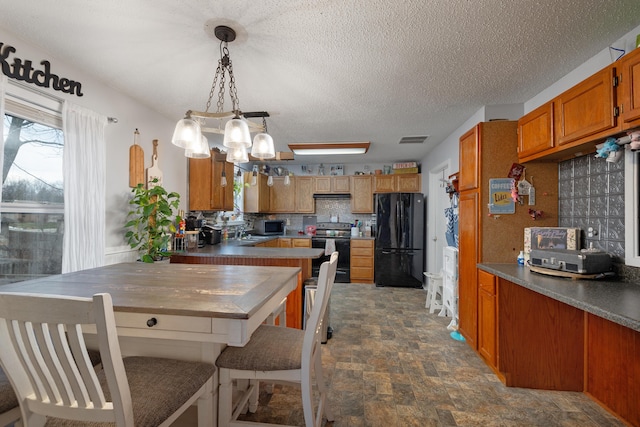 kitchen with tasteful backsplash, black appliances, hanging light fixtures, a textured ceiling, and a chandelier