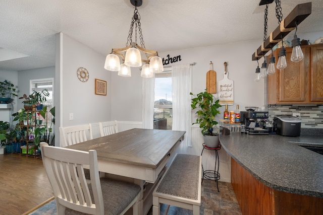 dining area featuring a textured ceiling, an inviting chandelier, and dark hardwood / wood-style floors