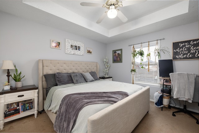 bedroom featuring ceiling fan, light colored carpet, and a tray ceiling