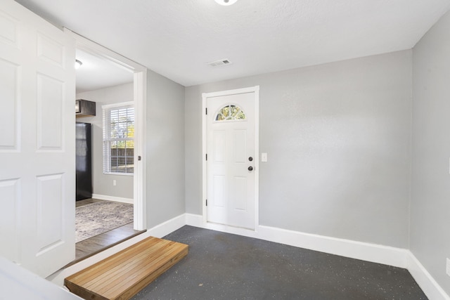 entryway featuring finished concrete floors, visible vents, and baseboards