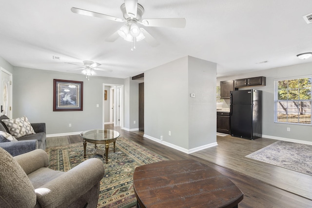 living area with visible vents, dark wood-type flooring, a ceiling fan, and baseboards