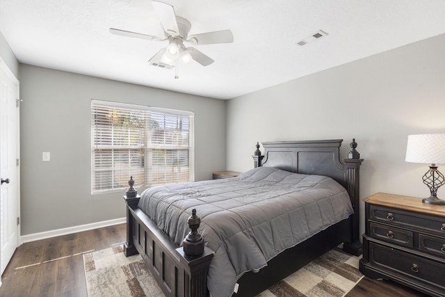 bedroom with dark wood-style floors, baseboards, visible vents, and ceiling fan