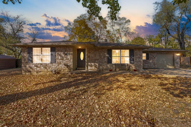 single story home with a garage, stone siding, and driveway