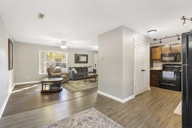 living room with rail lighting, visible vents, a ceiling fan, wood finished floors, and baseboards