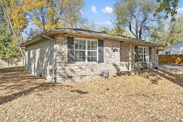 ranch-style house featuring stone siding and fence