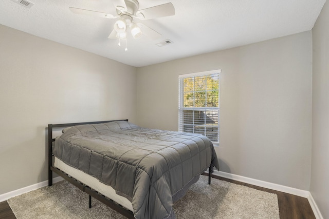 bedroom with a ceiling fan, baseboards, visible vents, and wood finished floors