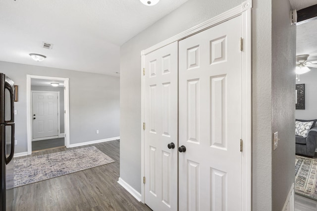 corridor with dark wood-type flooring, visible vents, and baseboards