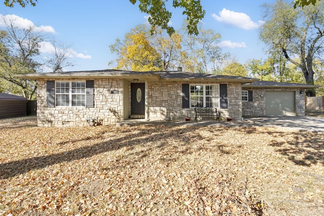 ranch-style home featuring an attached garage, stone siding, and concrete driveway