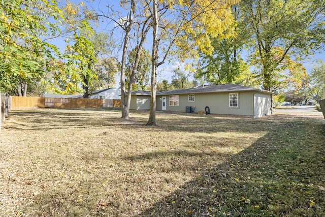 back of house with central AC, fence, and a lawn