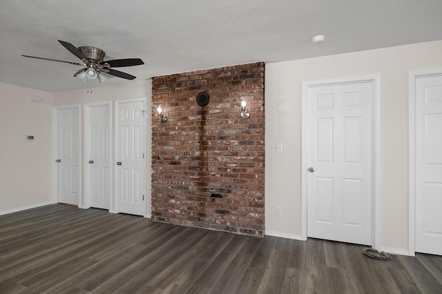 unfurnished bedroom with ceiling fan, dark wood-type flooring, a textured ceiling, and multiple closets