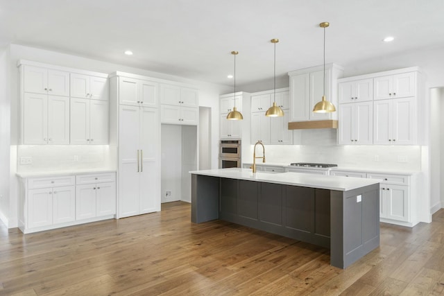 kitchen featuring white cabinets, sink, stainless steel appliances, and a center island with sink