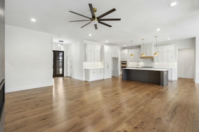 unfurnished living room featuring ceiling fan, dark hardwood / wood-style flooring, and sink