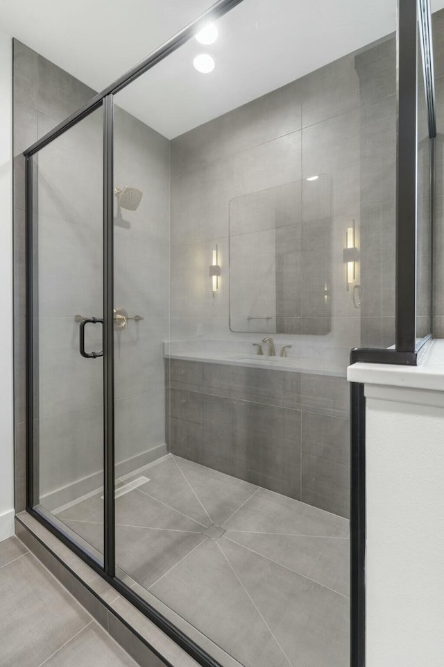 bathroom with a shower with shower door, tile patterned flooring, and sink