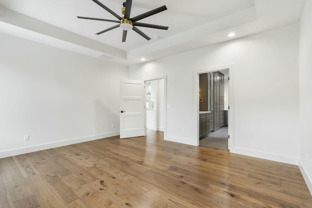 interior space with ceiling fan, light hardwood / wood-style floors, and a tray ceiling