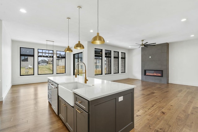 kitchen with a fireplace, sink, hanging light fixtures, ceiling fan, and stainless steel dishwasher