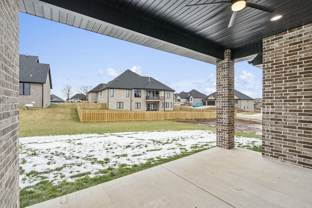 snow covered patio with ceiling fan and a yard