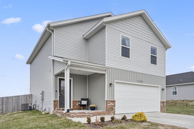 view of front of house with a garage, central air condition unit, a front yard, and covered porch