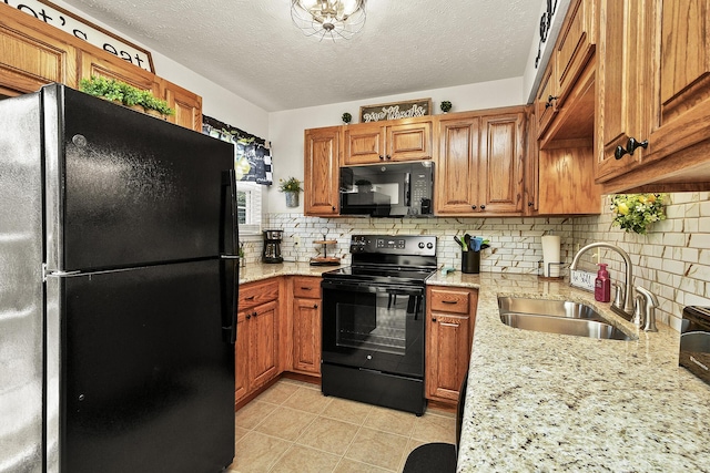 kitchen with light stone countertops, sink, black appliances, and tasteful backsplash