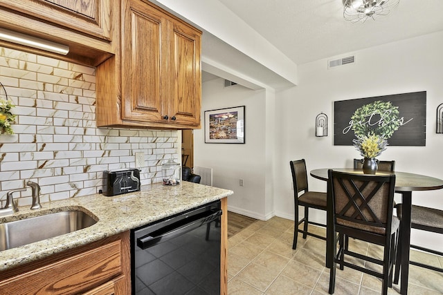 kitchen with light stone countertops, dishwasher, sink, and tasteful backsplash