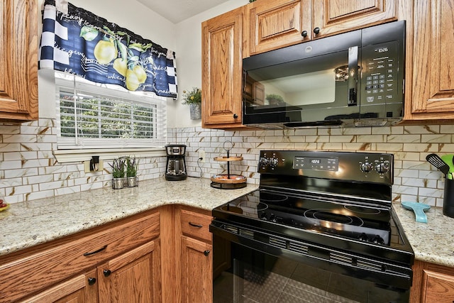 kitchen featuring light stone counters, backsplash, and black appliances