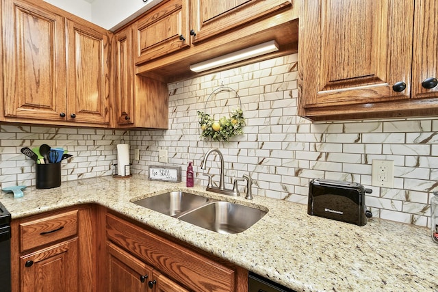 kitchen featuring light stone countertops, decorative backsplash, and sink