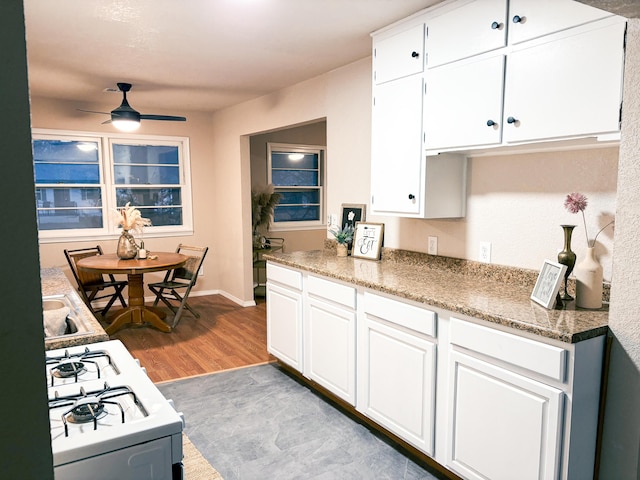 kitchen with ceiling fan, hardwood / wood-style floors, white range with gas stovetop, and white cabinets