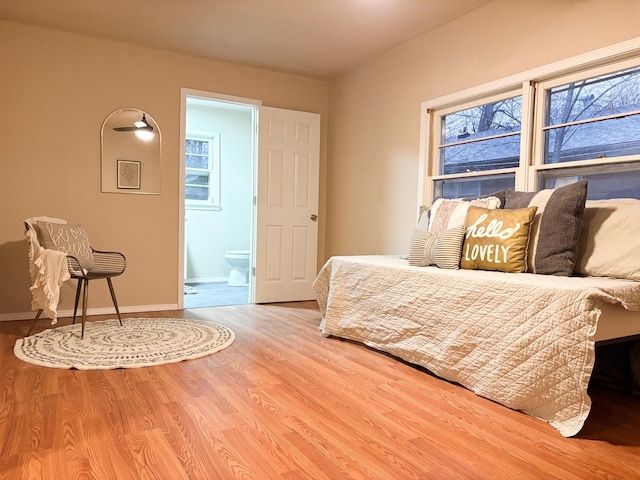 bedroom with connected bathroom and hardwood / wood-style flooring