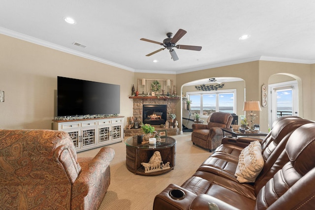 living room featuring ceiling fan, carpet, a fireplace, and ornamental molding