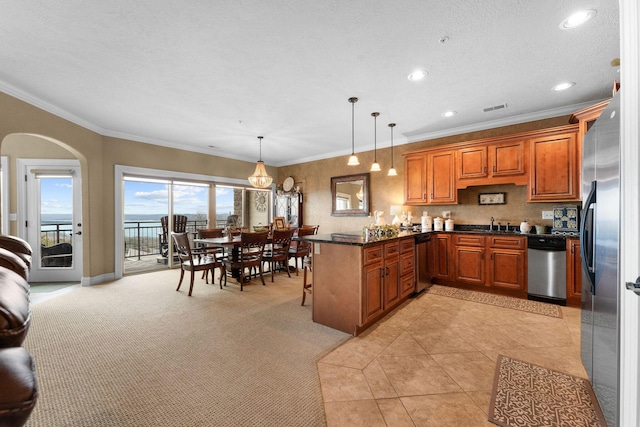 kitchen with decorative light fixtures, light colored carpet, crown molding, and stainless steel appliances