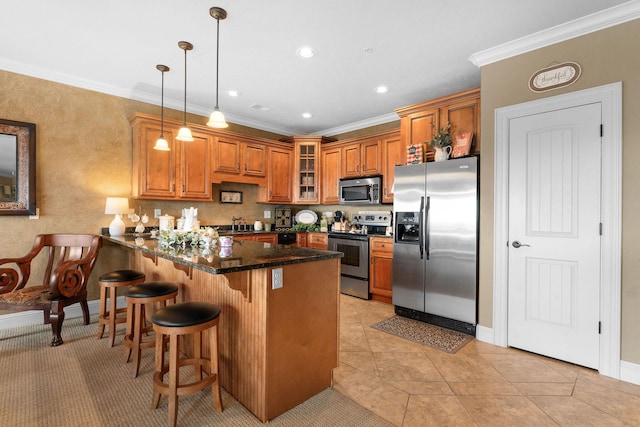 kitchen with appliances with stainless steel finishes, dark stone countertops, ornamental molding, and pendant lighting