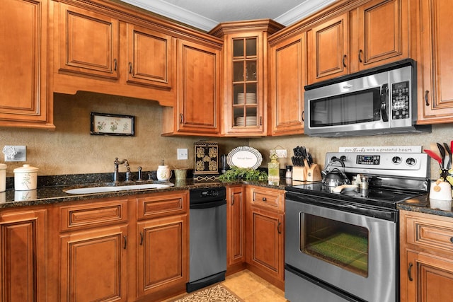 kitchen with appliances with stainless steel finishes, dark stone countertops, sink, ornamental molding, and light tile patterned flooring