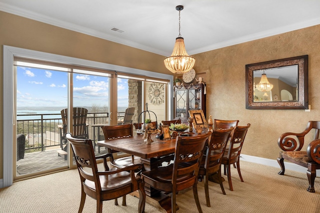 dining area featuring light carpet, a water view, a notable chandelier, and ornamental molding