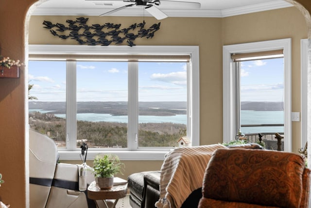 living area with ceiling fan, plenty of natural light, ornamental molding, and a water view