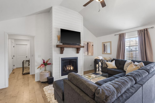 living room with ceiling fan, lofted ceiling, a fireplace, and light hardwood / wood-style flooring