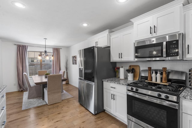 kitchen with decorative backsplash, light stone countertops, white cabinets, and stainless steel appliances