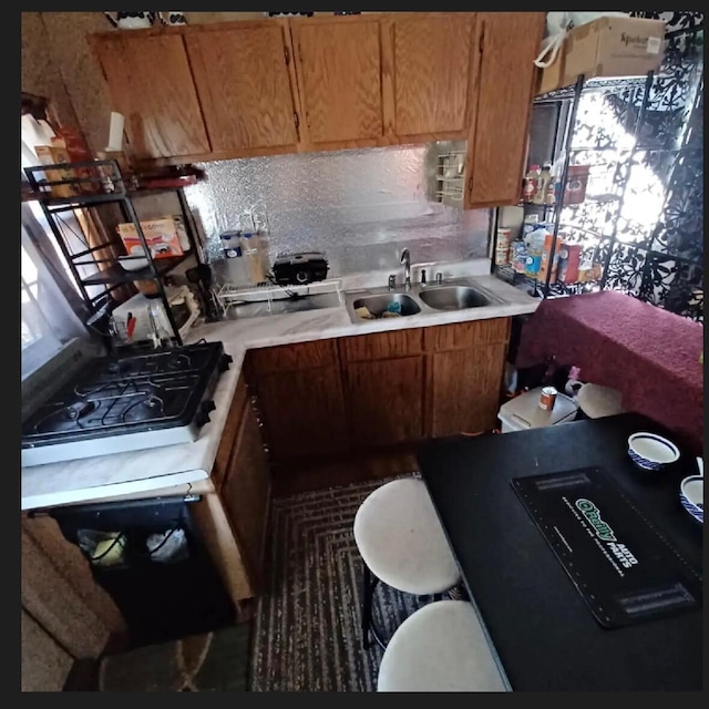389 Osage Ln, Pineville, MO 64856 - kitchen with brown cabinetry, a sink, backsplash, and light countertops