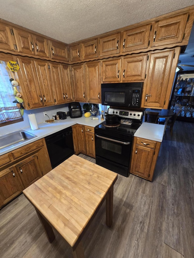 kitchen with black appliances, dark hardwood / wood-style flooring, sink, and a textured ceiling