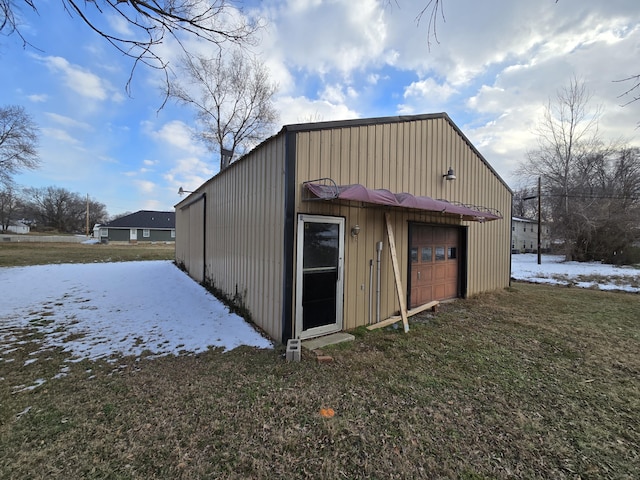 snow covered structure featuring a garage and a yard