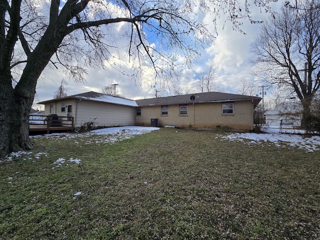 snow covered rear of property with a lawn and a wooden deck