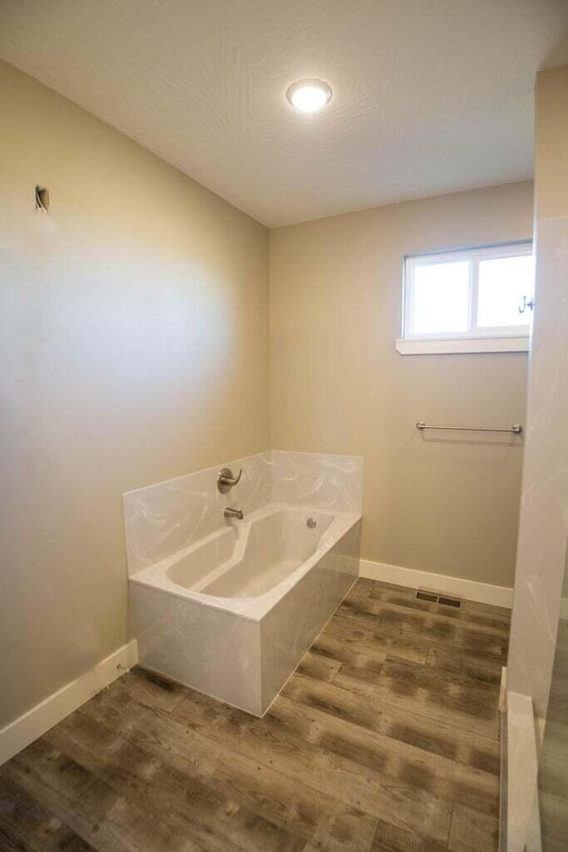 bathroom with hardwood / wood-style floors and a bath