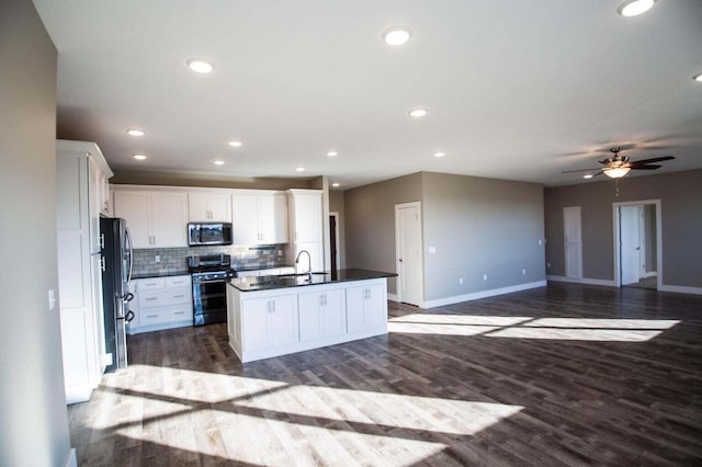 kitchen with appliances with stainless steel finishes, a kitchen island with sink, dark hardwood / wood-style flooring, white cabinets, and sink