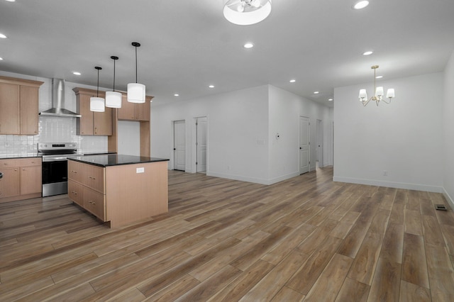 kitchen featuring a kitchen island, pendant lighting, stainless steel electric range, an inviting chandelier, and wall chimney exhaust hood