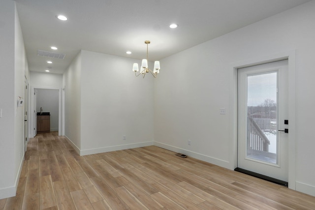 unfurnished dining area with a chandelier and light hardwood / wood-style floors