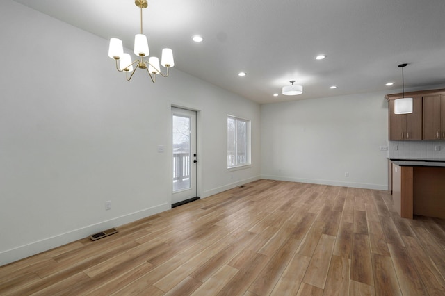 unfurnished living room with light hardwood / wood-style floors and a chandelier