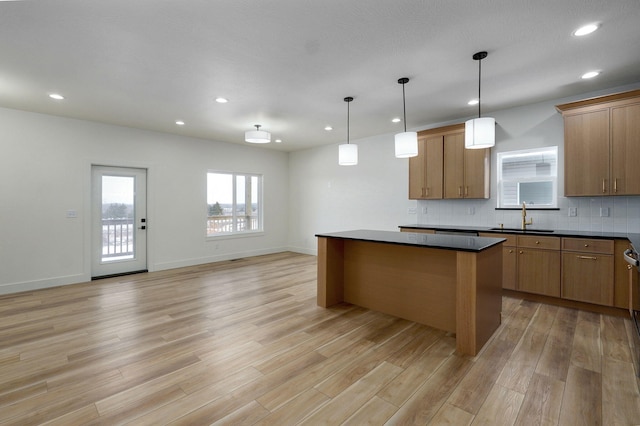 kitchen with sink, light hardwood / wood-style flooring, hanging light fixtures, and a center island