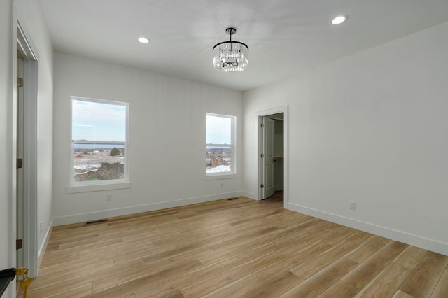 empty room featuring light wood-type flooring and an inviting chandelier