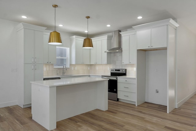 kitchen featuring white cabinets, wall chimney exhaust hood, a kitchen island, sink, and electric range