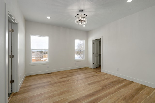 unfurnished room with light hardwood / wood-style floors and a chandelier